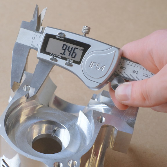 Closeup of hand holding digital vernier gauge measuring an aluminium machined part